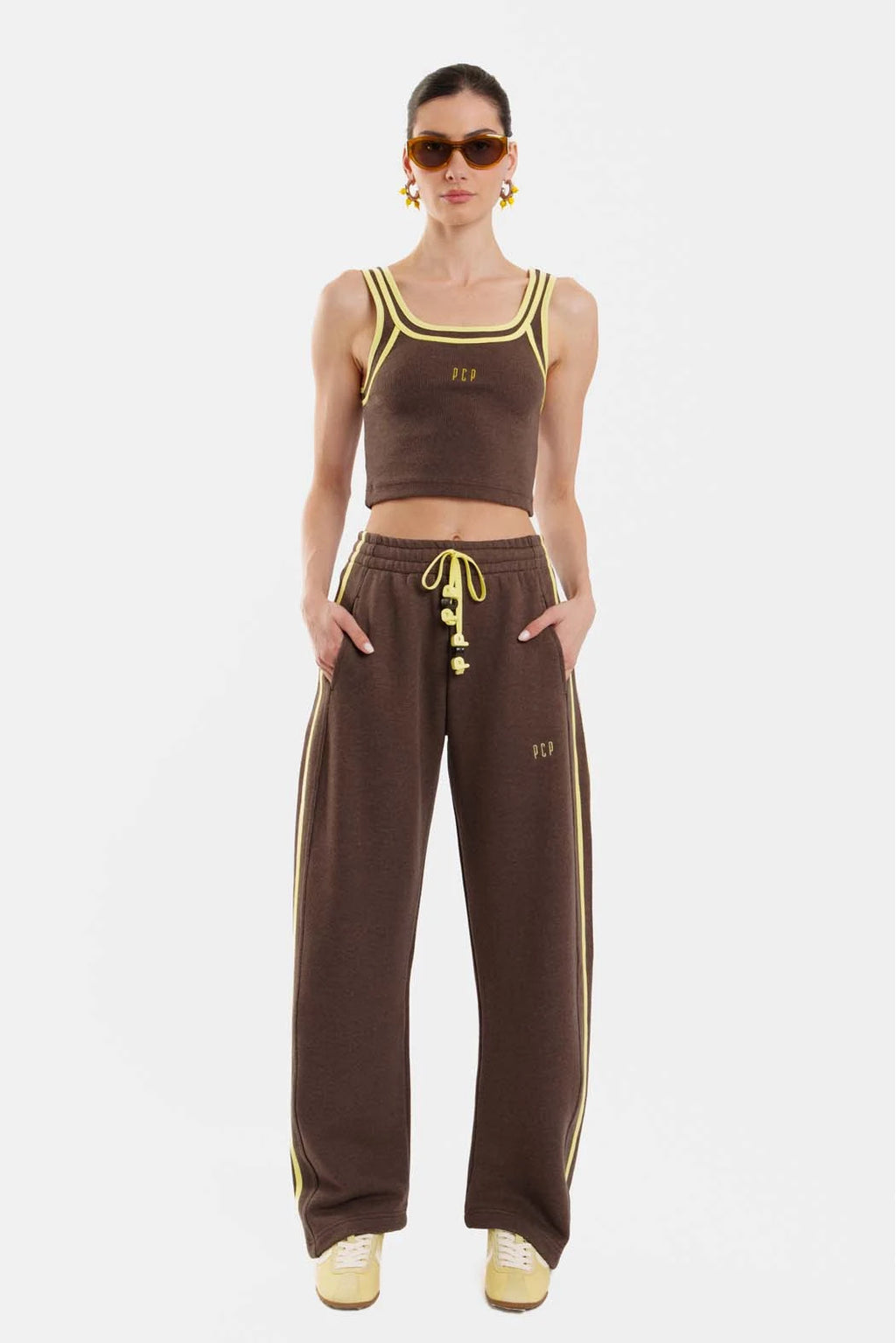 Woman wearing a brown sports outfit with yellow accents on a white background