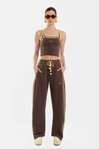 Woman wearing a brown sports outfit with yellow accents on a white background