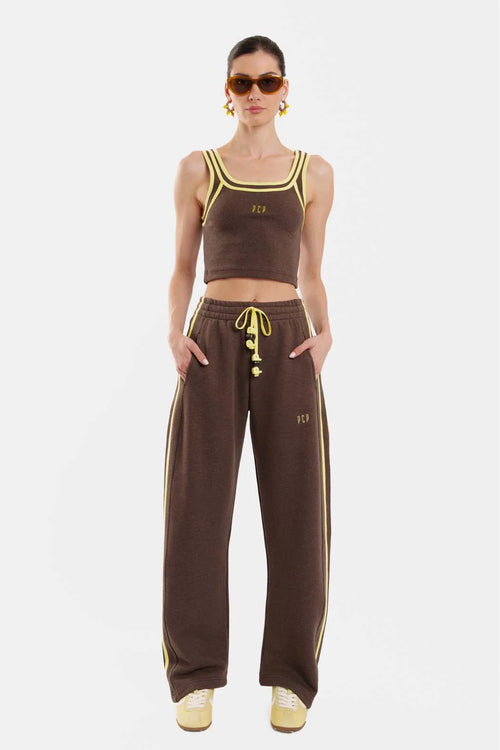 Woman wearing a brown sports outfit with yellow accents on a white background