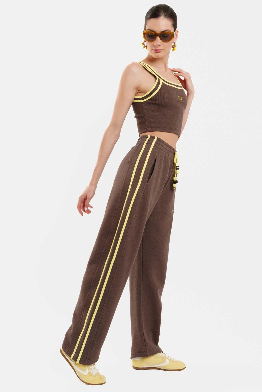 Woman wearing a brown outfit with yellow accents on a white background