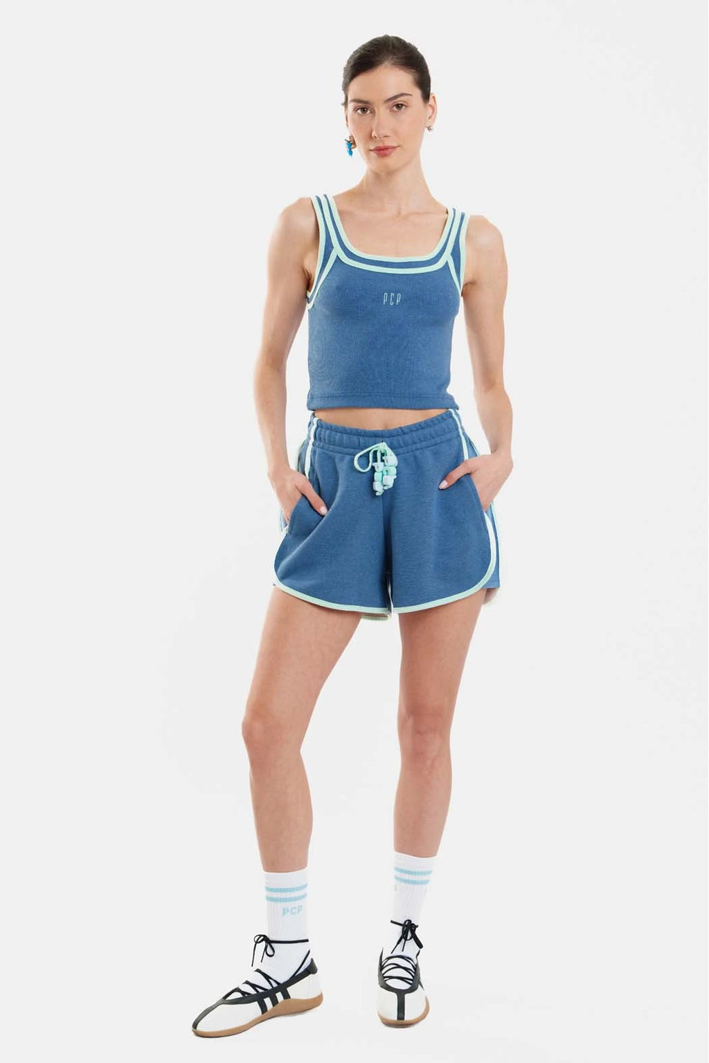 Woman wearing a blue tank top and shorts set on a white background