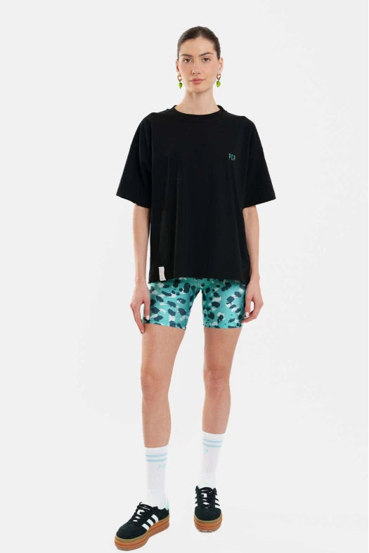 Person wearing a black t-shirt and patterned shorts on a white background