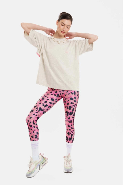 Person wearing a beige oversized shirt and pink leopard print leggings on a white background
