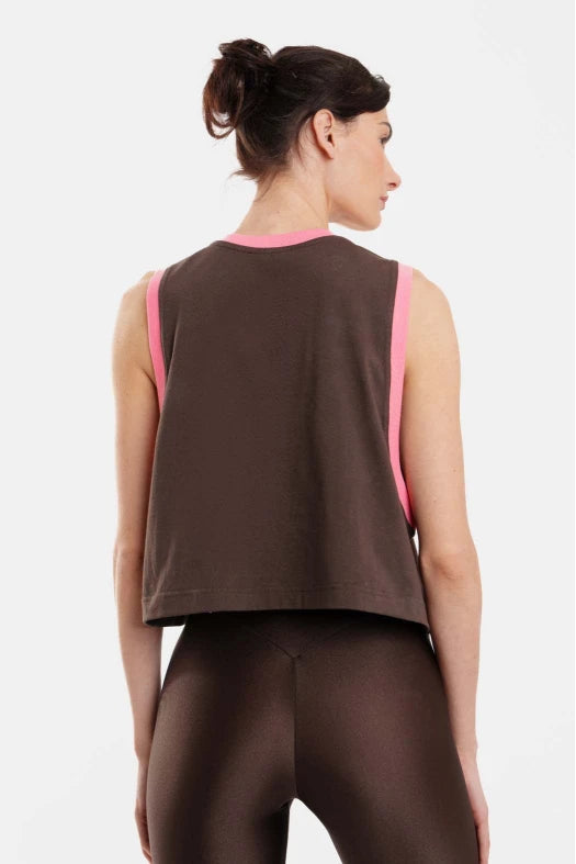 Woman wearing a brown sleeveless top with pink accents on a white background