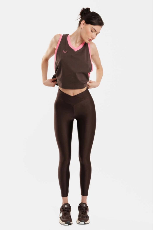 Woman wearing a brown athletic outfit with pink accents on a white background