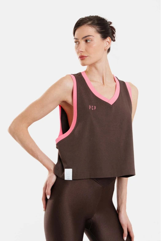 Woman wearing a brown tank top with pink trim on a white background