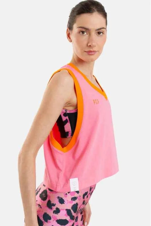 Woman wearing a pink tank top with orange trim and patterned leggings on a white background