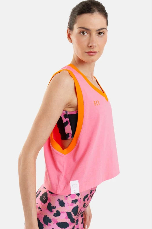 Woman wearing a pink tank top with orange trim and patterned leggings on a white background