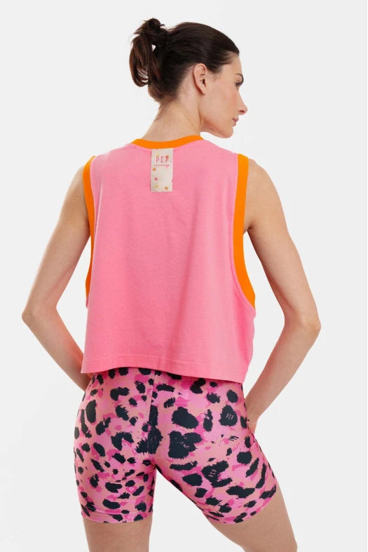 Woman wearing a pink sleeveless top and leopard print shorts on a white background