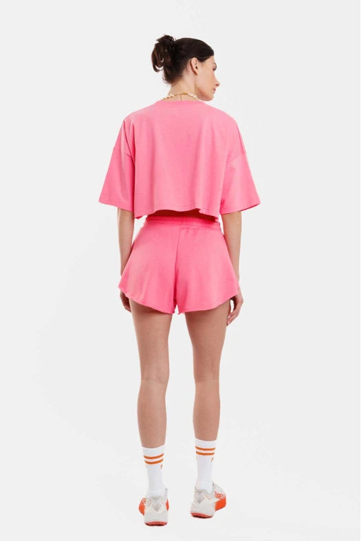 Person wearing a pink outfit with shorts and a cropped top on a white background