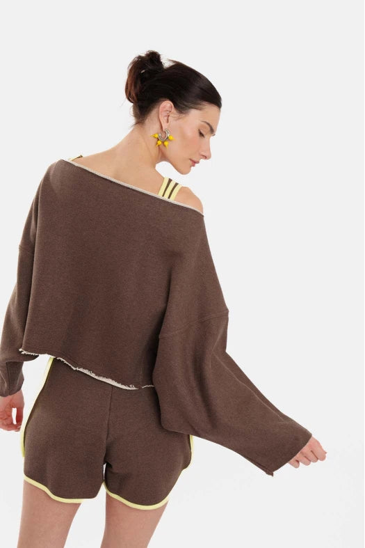 Woman wearing a brown off-shoulder top and shorts set on a white background