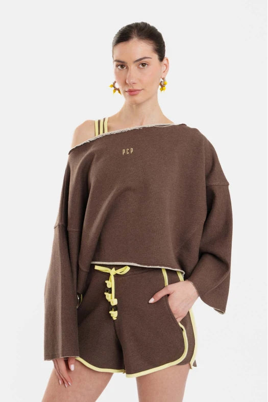 Woman wearing a brown off-shoulder top and shorts with yellow accents on a white background