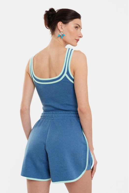 Woman wearing a blue romper with white trim on a light gray background