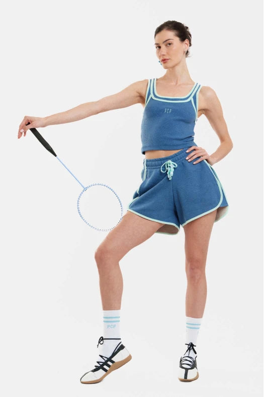 Woman in blue athletic outfit holding a badminton racket on a white background