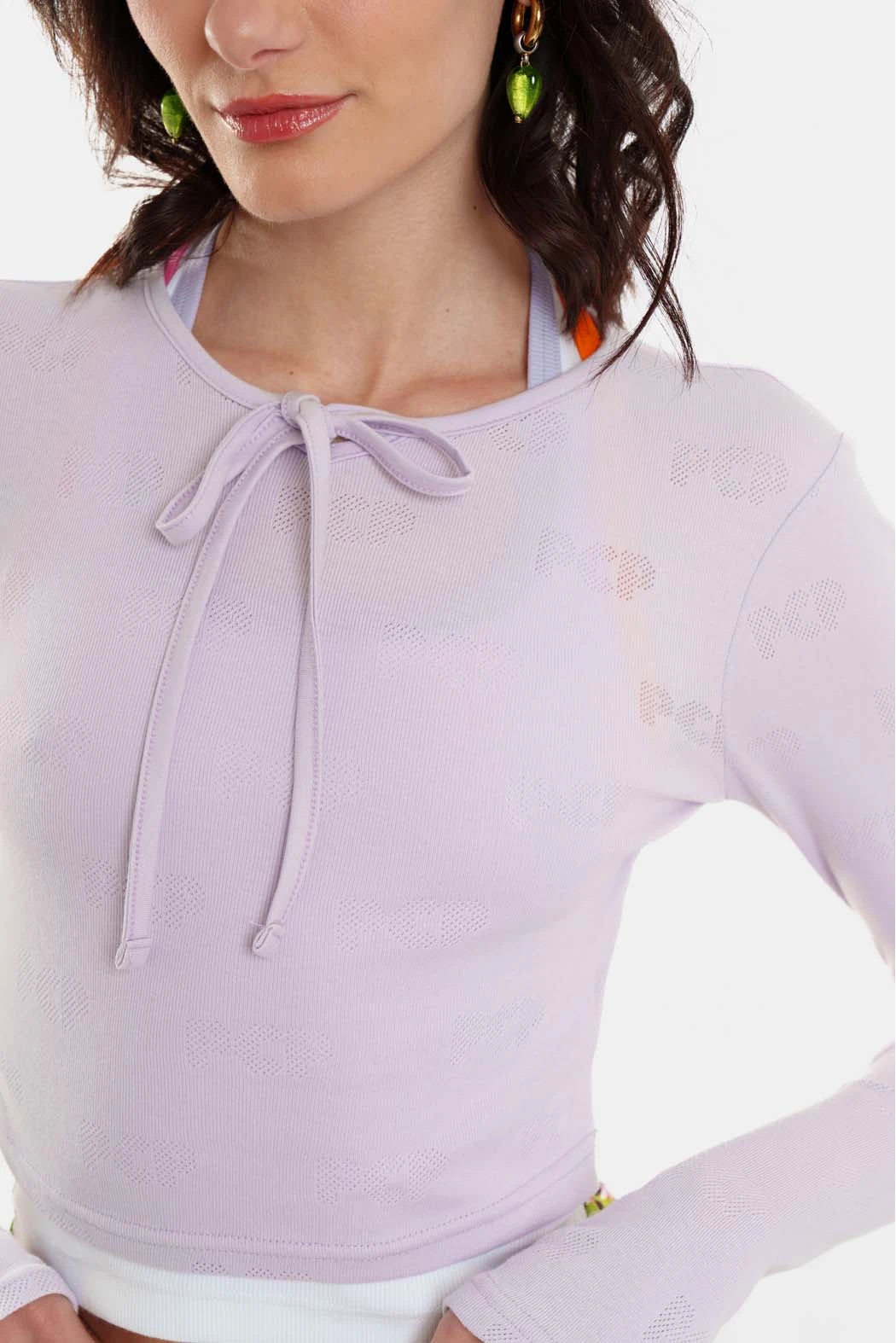 Woman wearing a light purple long-sleeve top with a bow neckline on a white background