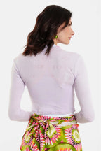 Woman wearing a light purple long-sleeve top and colorful skirt on a white background