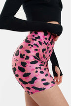 Person wearing pink and black patterned shorts with a plain background