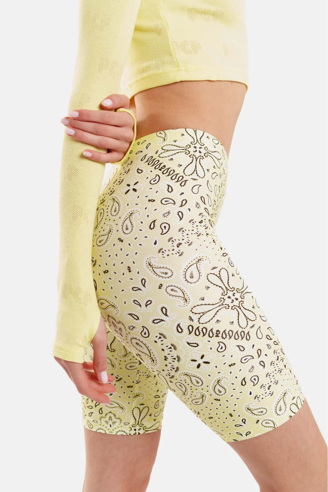 Person wearing yellow patterned shorts with a plain background