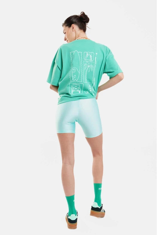 Person wearing a green t-shirt and shorts with a logo, standing against a white background