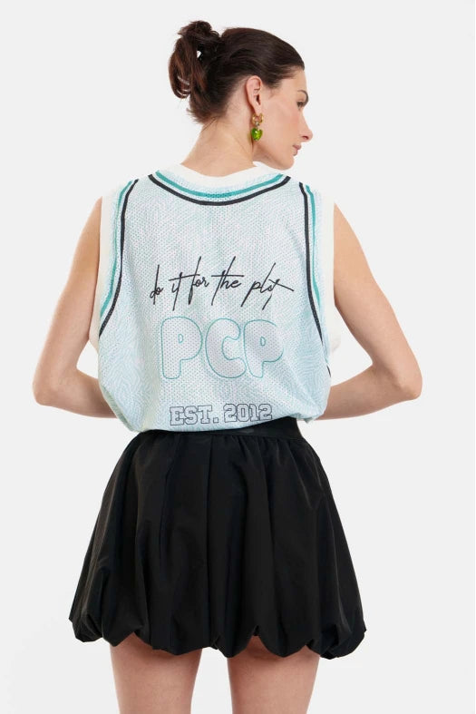 Woman wearing a light blue sleeveless top with text and a black skirt on a white background