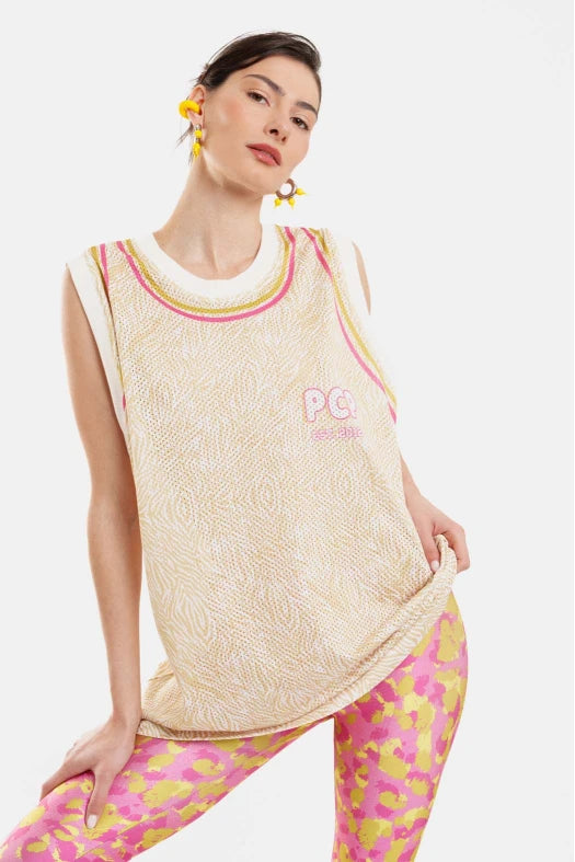 Woman wearing a beige sleeveless top with pink accents and pink and yellow patterned leggings on a white background