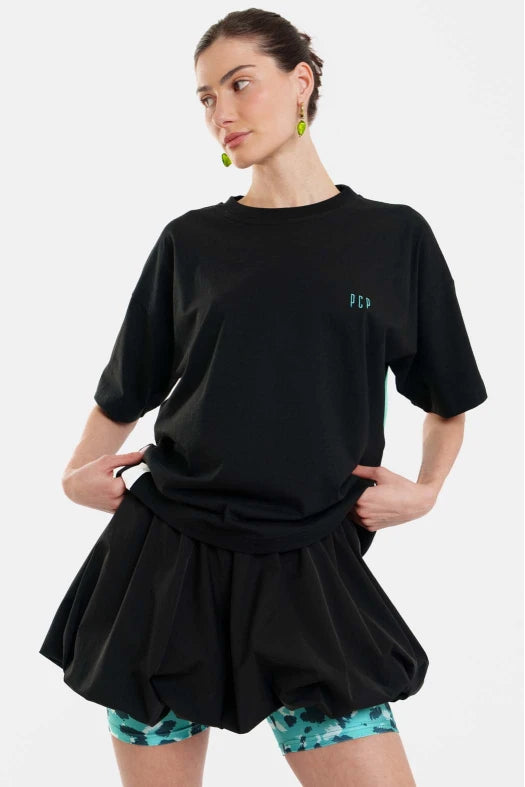 Woman wearing a black oversized t-shirt and black shorts with floral leggings on a white background