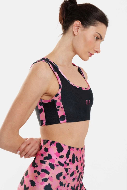Woman wearing a black and pink sports bra with matching leggings on a white background