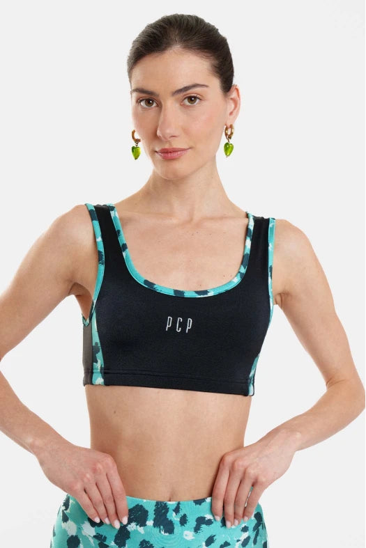 Woman wearing a black sports bra with floral trim and matching shorts on a white background