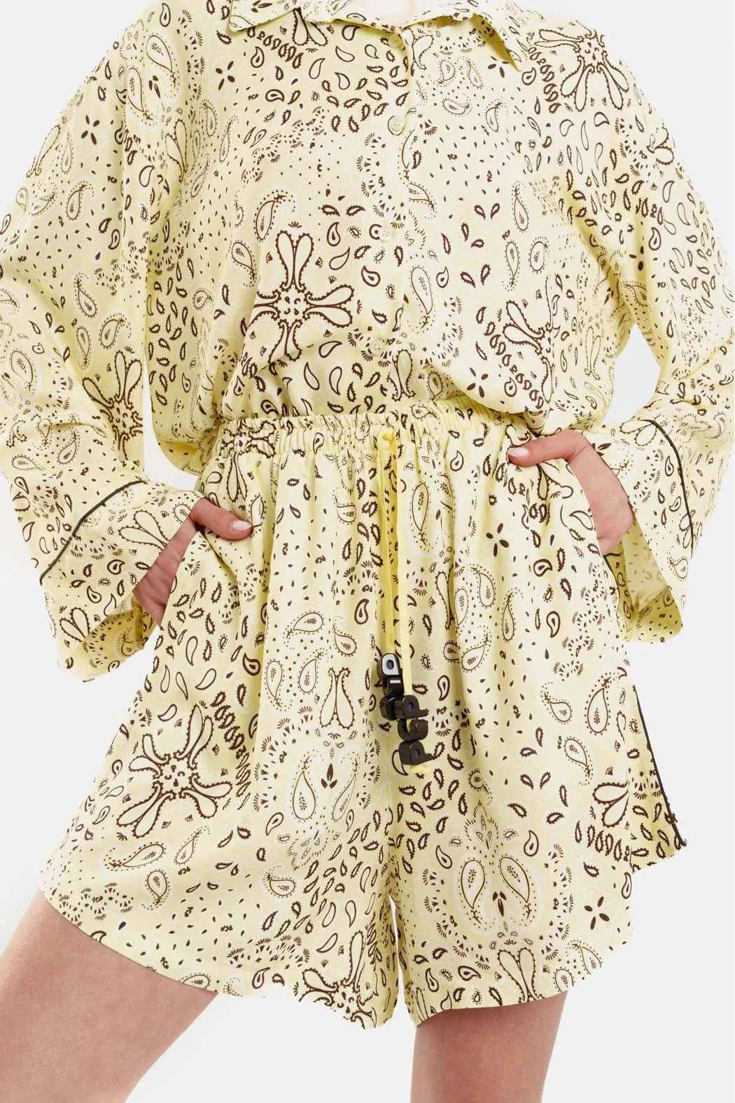 Yellow patterned dress with long sleeves and a belt on a white background