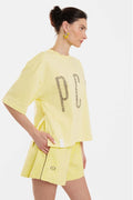 Woman wearing a yellow outfit with 'PCP' branding on a white background