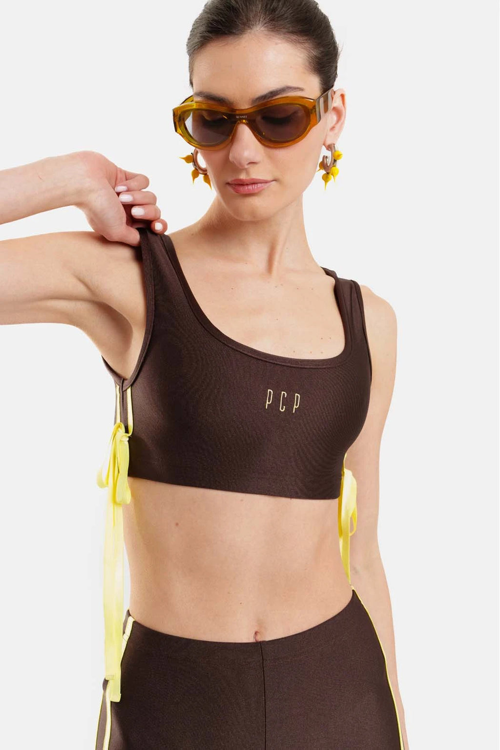 Woman wearing a brown sports bra with 'PCP' branding on a white background