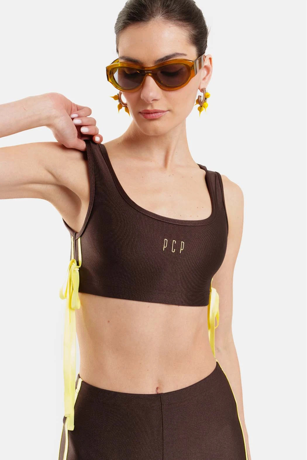 Woman wearing a brown sports bra with 'PCP' branding on a white background