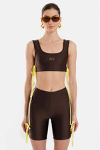 Woman wearing a brown sports outfit with yellow accents on a white background