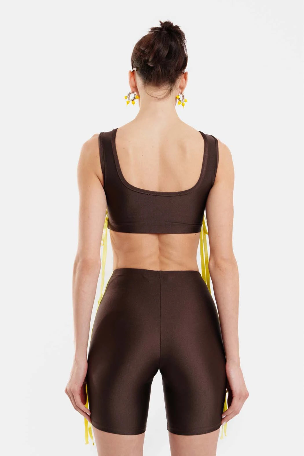 Person wearing a brown sports bra and shorts set on a white background