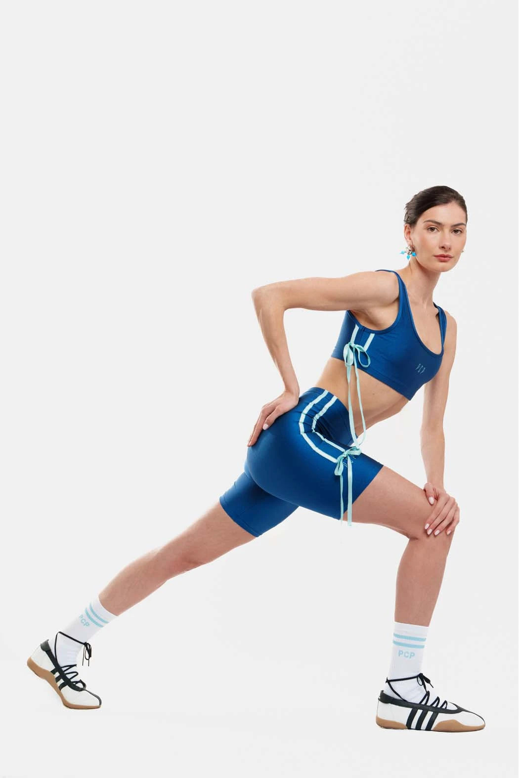 Woman in blue athletic outfit posing on a white background