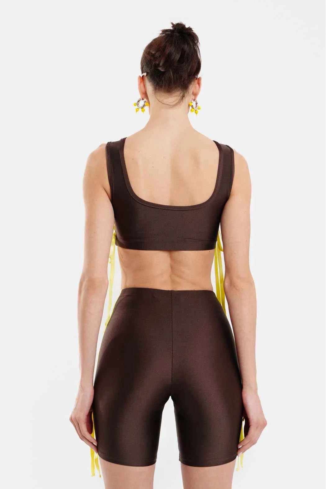 Woman wearing a brown sports bra and shorts set on a white background