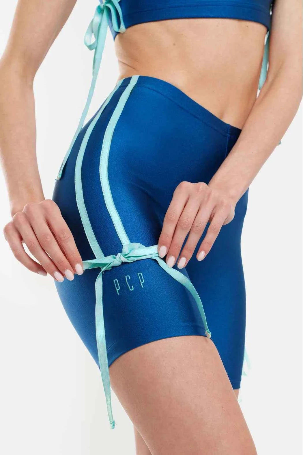 Blue athletic shorts with green straps on a white background