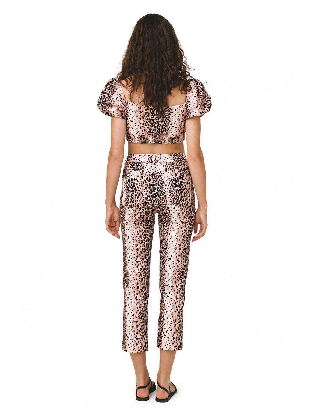 A model viewed from the back wearing a matching two-piece leopard print set with puff sleeves and cropped pants, on a plain white background.