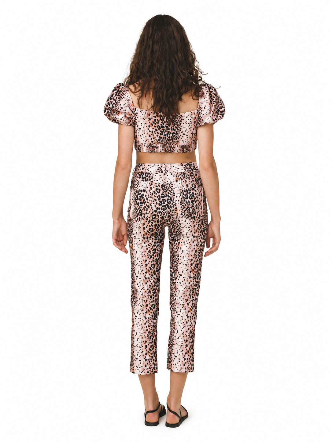 A model viewed from the back wearing a matching two-piece leopard print set with puff sleeves and cropped pants, on a plain white background.