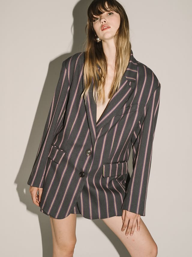 Woman wearing a striped blazer and skirt set against a plain background