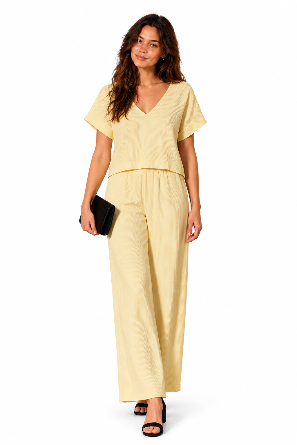 A woman modeling a pale yellow short-sleeve jumpsuit with a V-neckline and wide-leg pants, holding a small black clutch against a plain white background.