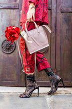 Person holding a pink handbag and a red rose in front of a wooden door.