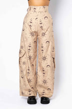 Beige pants with star and moon pattern worn by a person on a white background