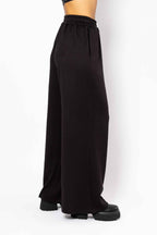 Black wide-leg pants worn by a person on a white background