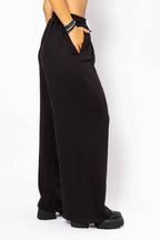 Black wide-leg pants worn by a person on a white background
