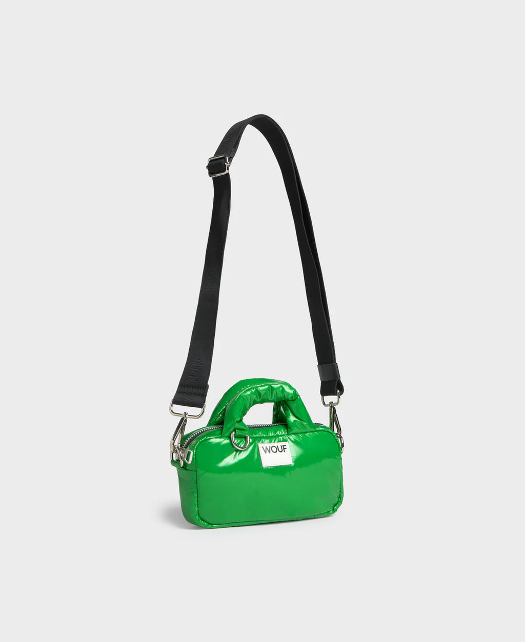 Green handbag with a black strap on a light gray background