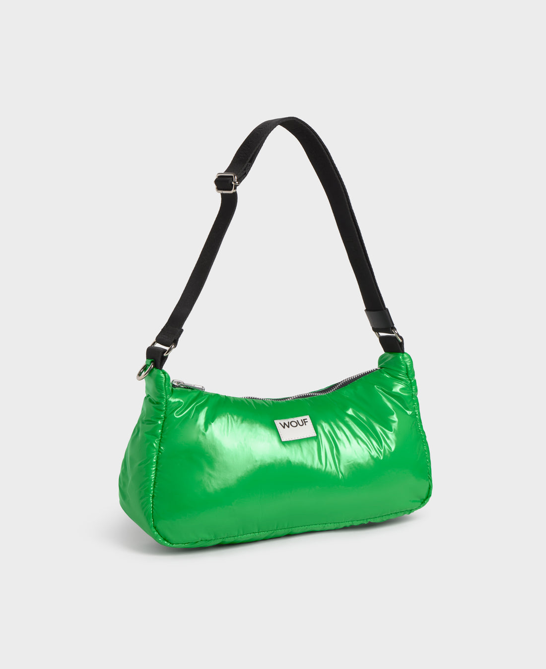 Green handbag with a black strap on a light gray background