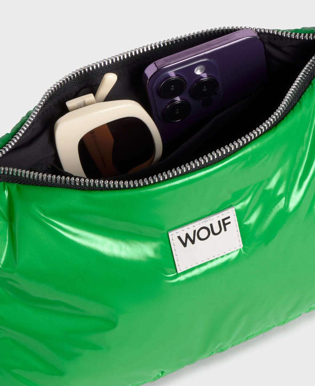 Green bag with a phone and sunglasses, featuring the WOUF brand.