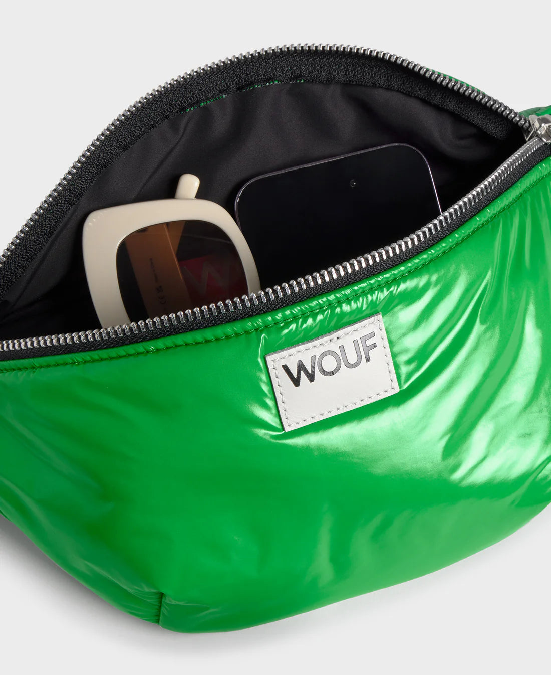 Green fanny pack with sunglasses and phone, featuring WOOF brand logo.