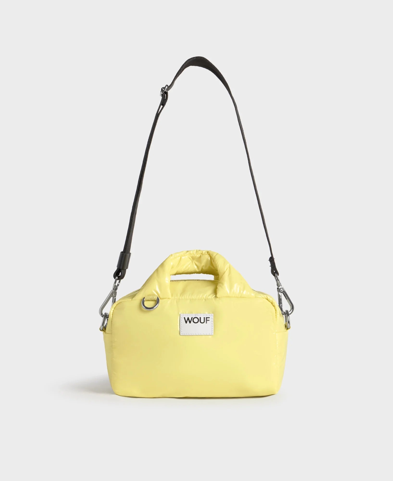Yellow handbag with a black strap on a light gray background